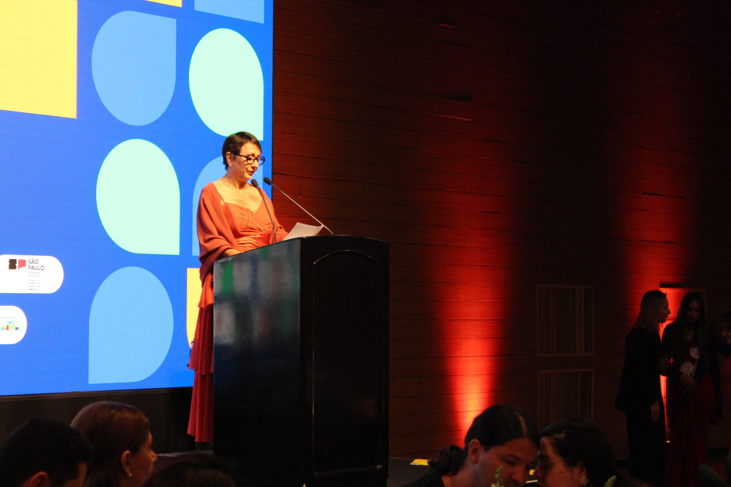 A photo of a woman on stage speaking into a microphone at the WBU World Blindness Summit.