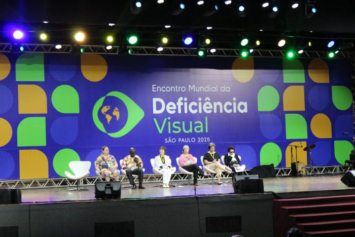 2025年於巴西聖保羅舉行的世界盲人聯盟大會上，六位講者站在舞台上，背景是色彩繽紛的藍色布景，並配有地球標誌。